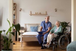 Care staff guide an older resident with a walker through a well-lit assisted living hallway during an evacuation drill.