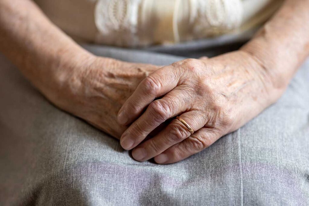 An older adult laughs with a family member while arranging keepsakes in a cozy apartment.